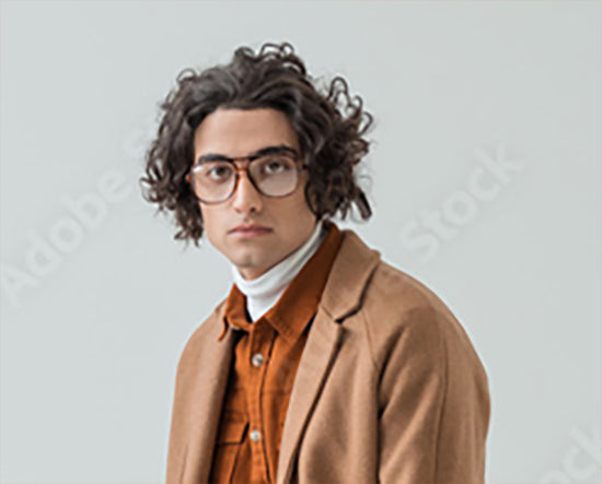 Man wearing glasses and a brown coat against a light gray background