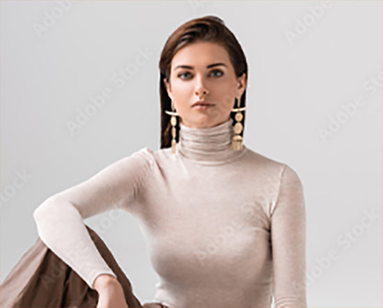 Woman wearing a beige turtleneck sweater against a plain background