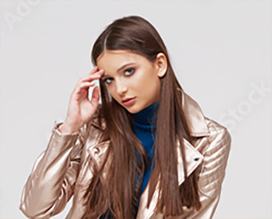 Woman wearing a shiny beige jacket against a plain background