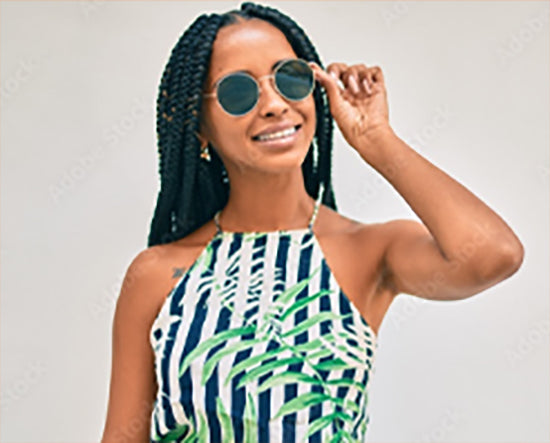 Woman wearing sunglasses and a patterned dress against a plain background