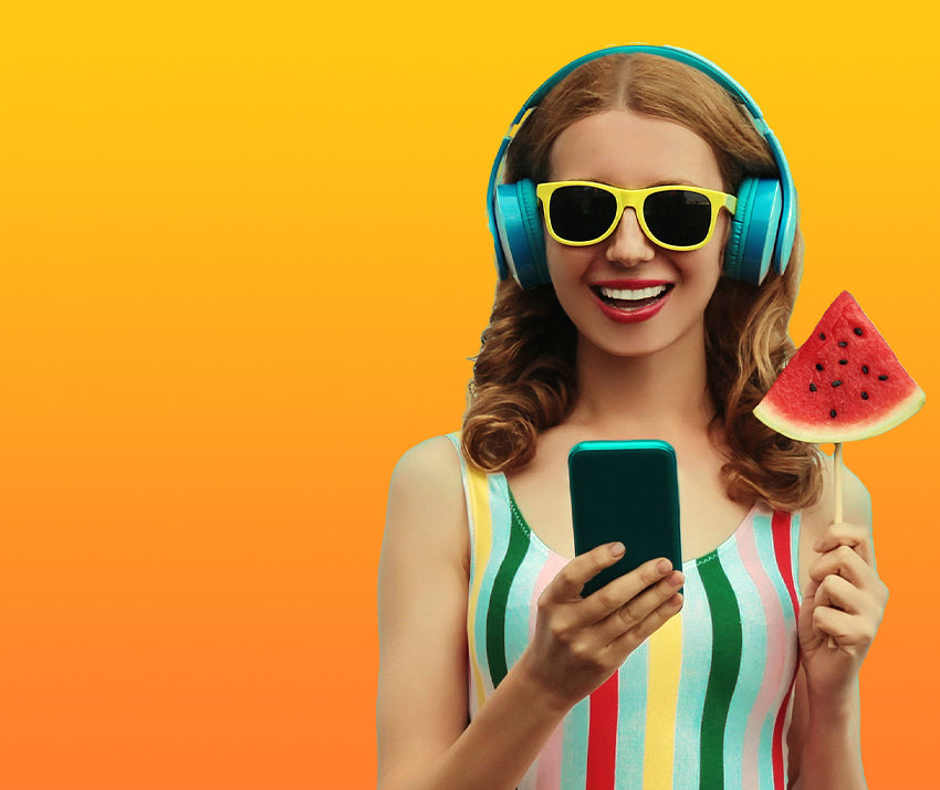 Woman wearing headphones and sunglasses, holding a phone and watermelon slice, on an orange background